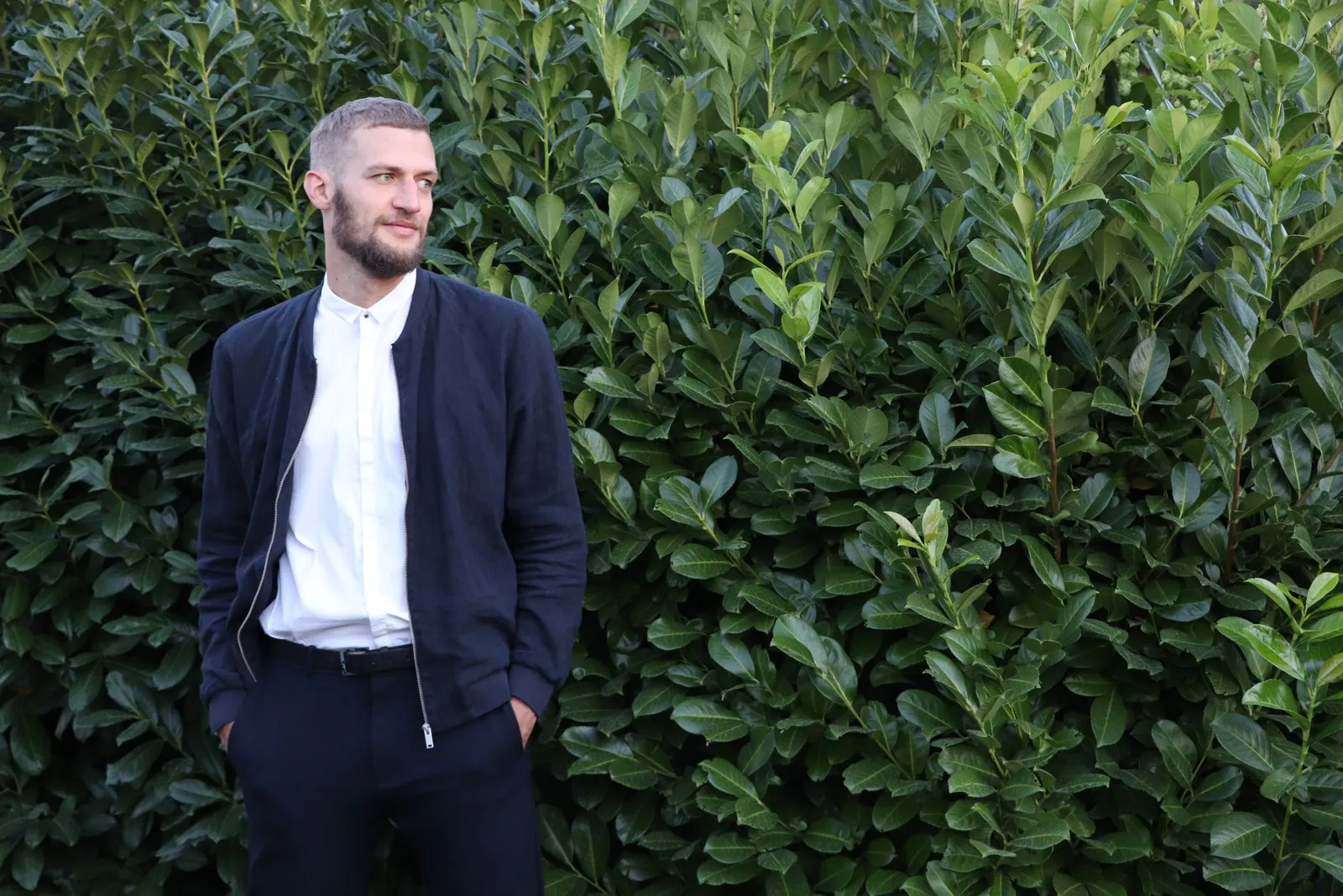 Porträt von Toni Karge vor einer grünen Hecke